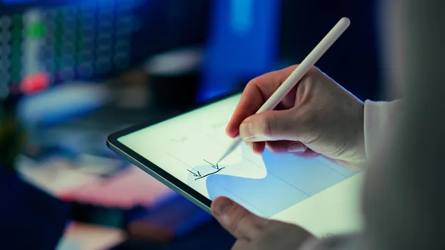 Business person using a stylus to analyze data on a digital tablet in an office setting. Beratungsleistungen strukturiert vergleichen