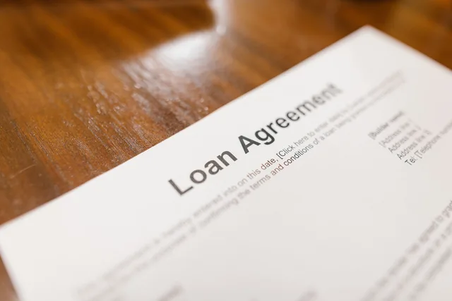 Detailed loan agreement document close-up on a wooden table representing legal and financial concepts. Vertragsbedingungen für Dienstleistungen verstehen
